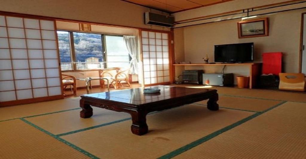 een woonkamer met een salontafel en een televisie bij Oyado Matsubaya / Vacation STAY 8063 in Obinata