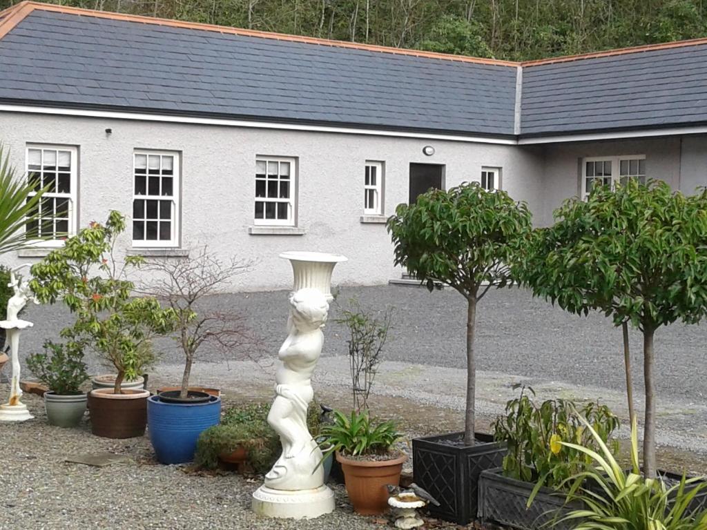 a white statue in front of a house with plants at Necarne Manor Apartment in Irvinestown