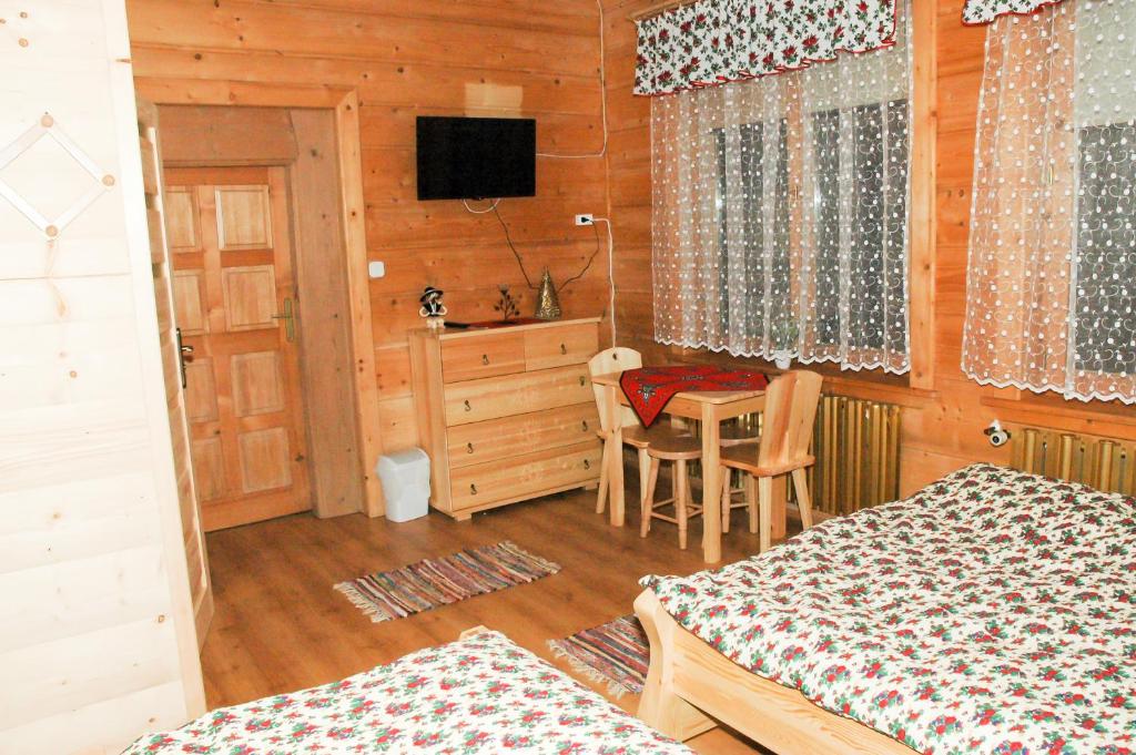 a bedroom with a bed and a table and a television at Willa Pod Stokiem in Witów