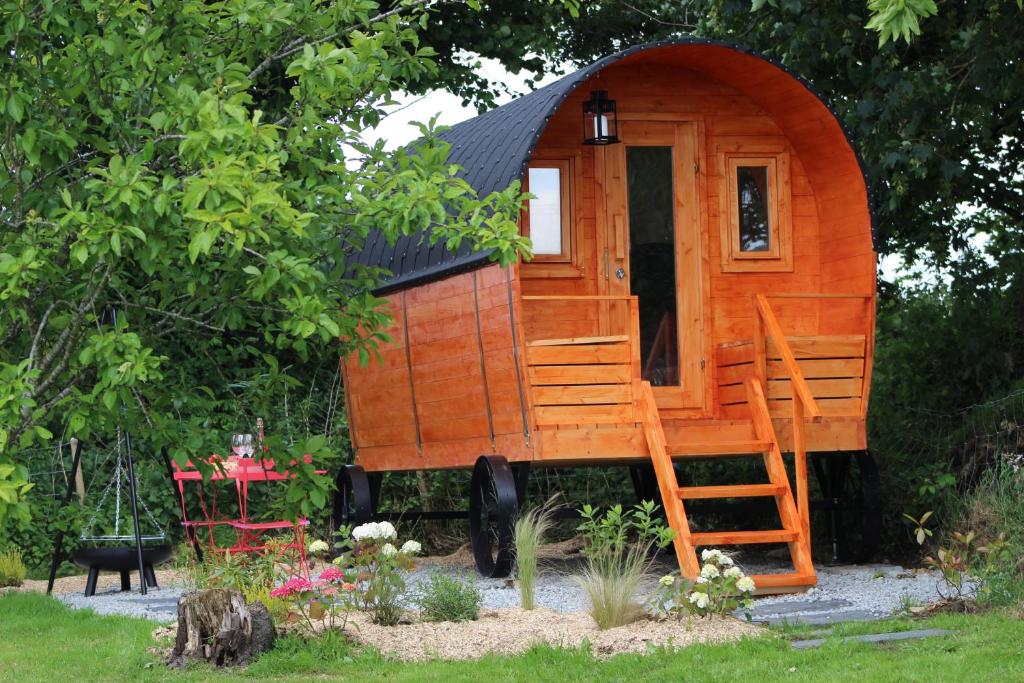 a wooden cabin with a ladder in a garden at Insolites en Mené in Saint-Vran