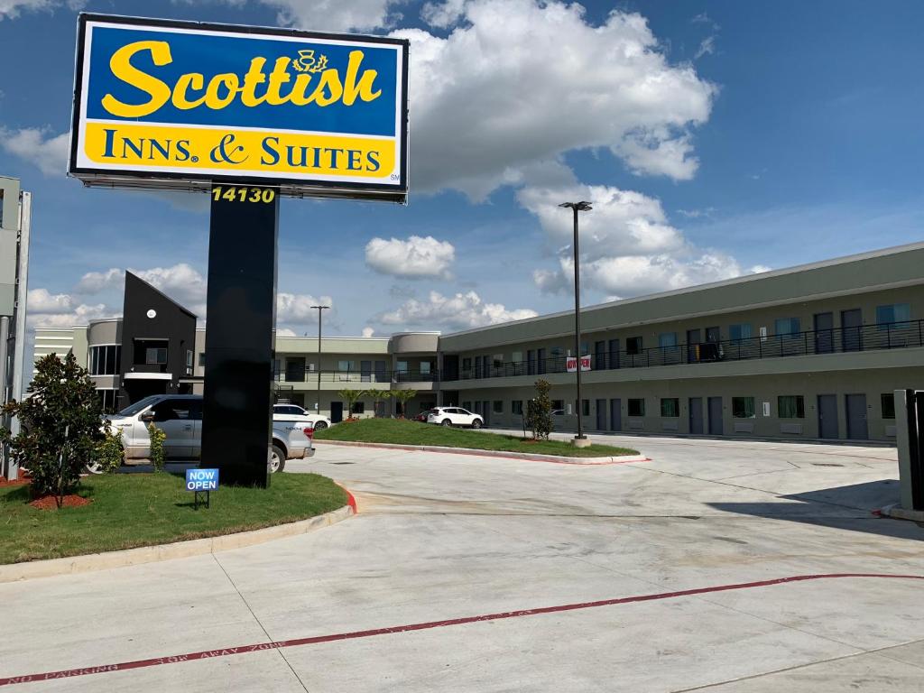 una señal para una posada científica y suites en un estacionamiento en Scottish Inns and Suites Scarsdale en Houston