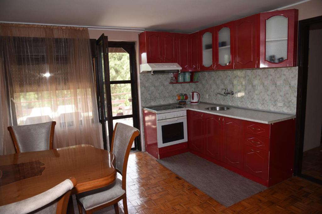 cocina con armarios rojos, mesa y comedor en Apartment Dedine Golubac, en Golubac