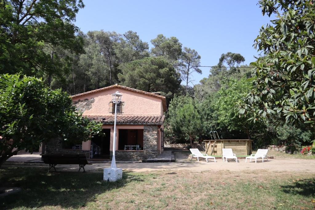 uma casa com cadeiras brancas e um grelhador num quintal em Masia Can Ninot em Santa Susanna