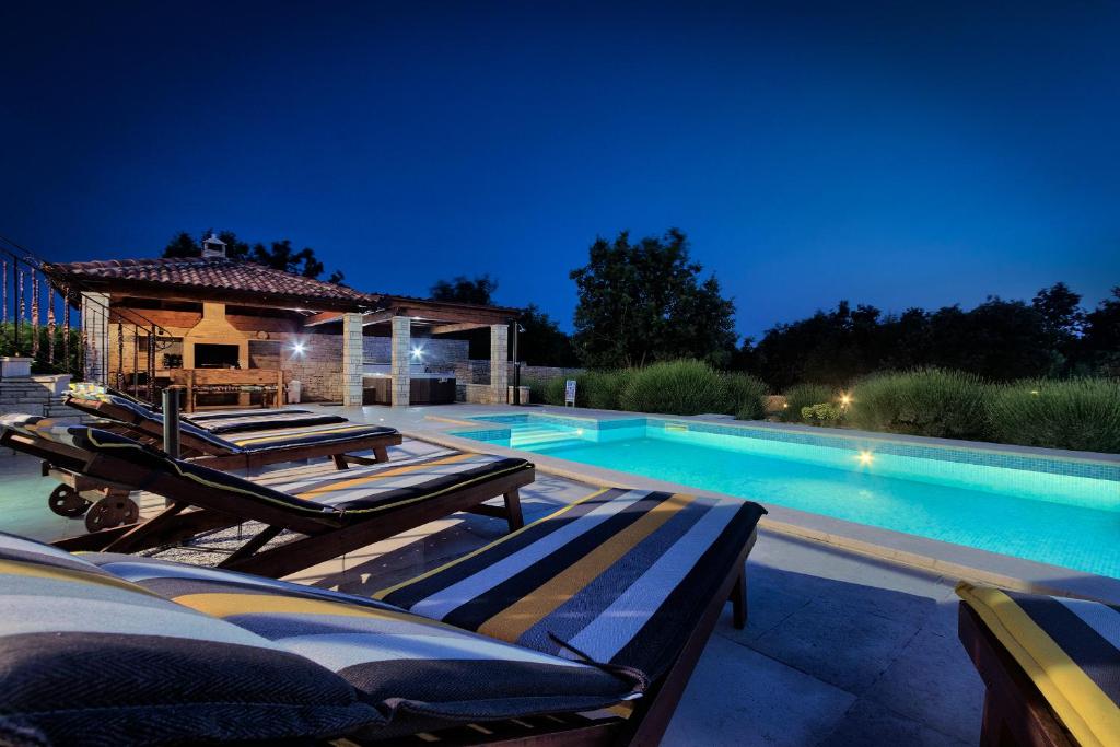 a swimming pool with lounge chairs and a gazebo at Villa Stokovci in Štokovci