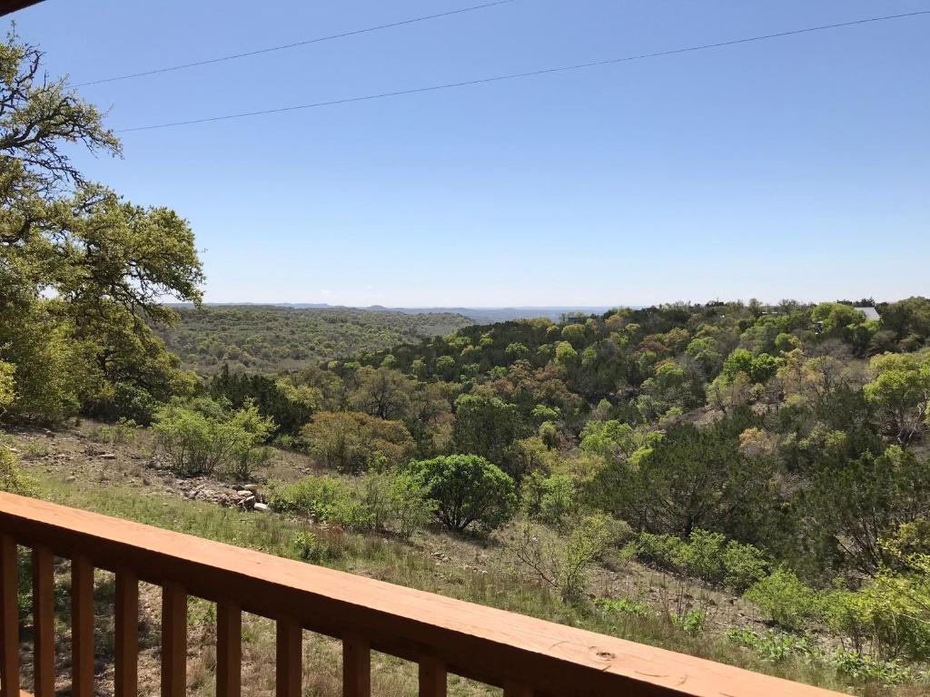 uma vista para uma floresta a partir de um deque de madeira em Walnut Canyon Cabins em Fredericksburg