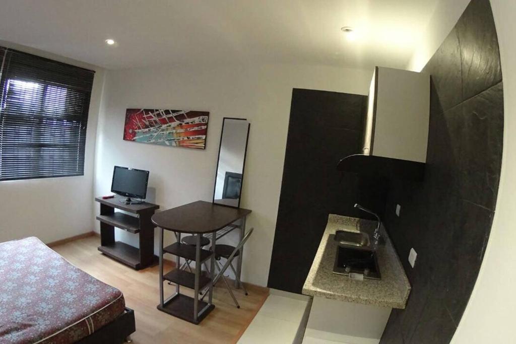 um pequeno quarto com uma cama e uma mesa com uma secretária em COSY STUDIO APARTMENT GREAT LOCATION (203) em Bogotá