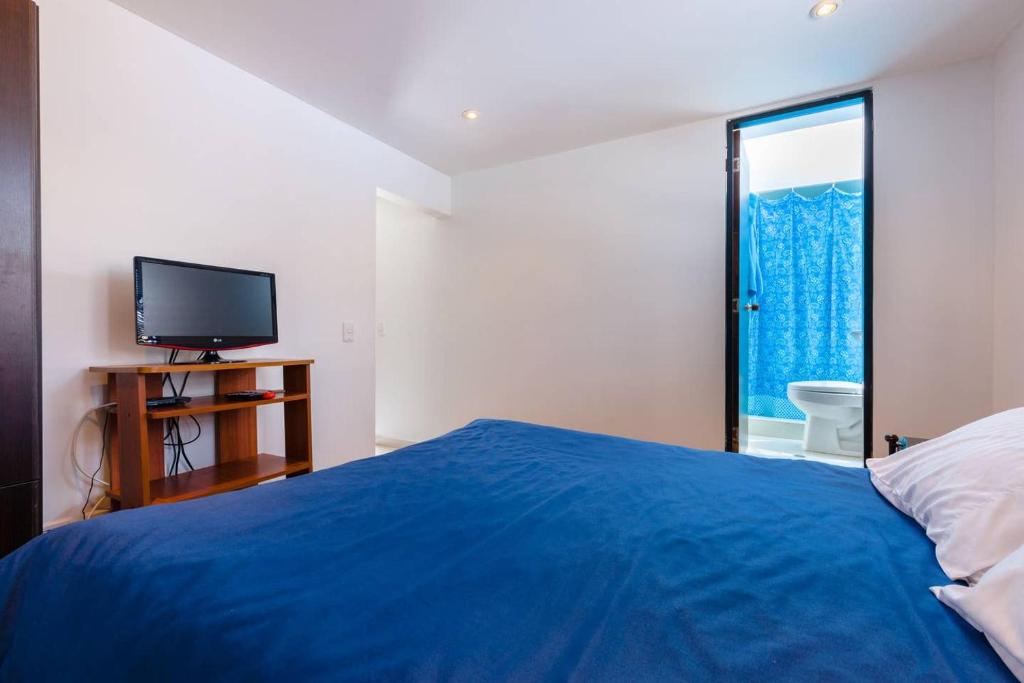 1 dormitorio con 1 cama azul y TV en LOFT APARTMENT IN CENTRAL LOCATION (301), en Bogotá
