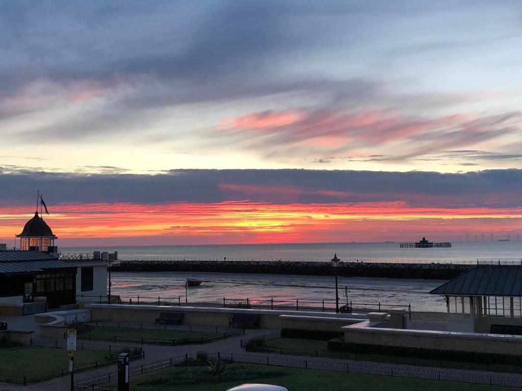 einen Sonnenuntergang über dem Meer mit einem Pier und einem Leuchtturm in der Unterkunft Imperial House Holiday Let in Herne Bay