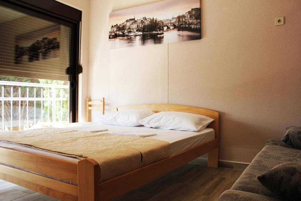 1 cama en un dormitorio con una foto en la pared en Mimoza Apartments, en Ðenovići