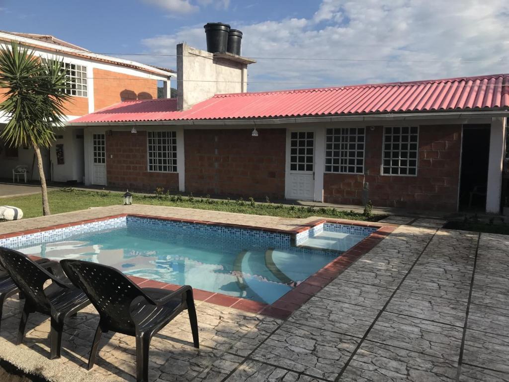 uma piscina com duas cadeiras e uma casa em La Luna by JR em Mariquita
