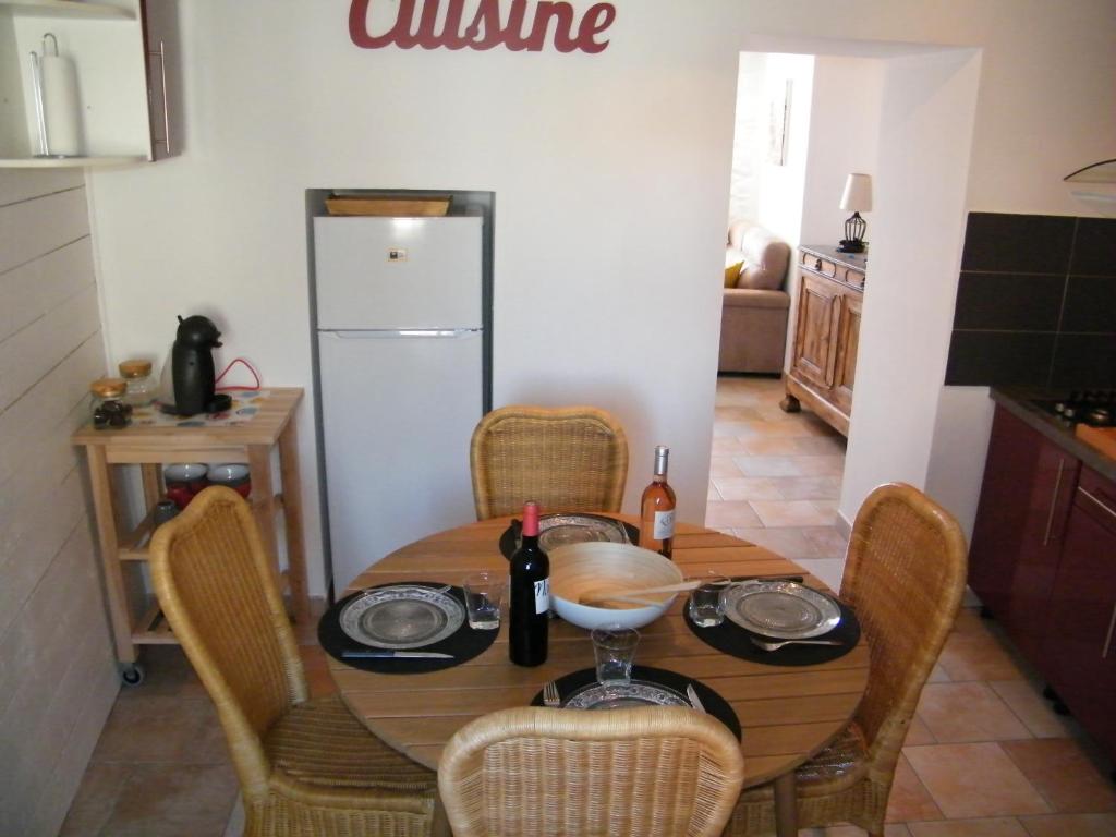 y cocina con mesa, sillas y nevera. en La petite Oustal, en Marseillette