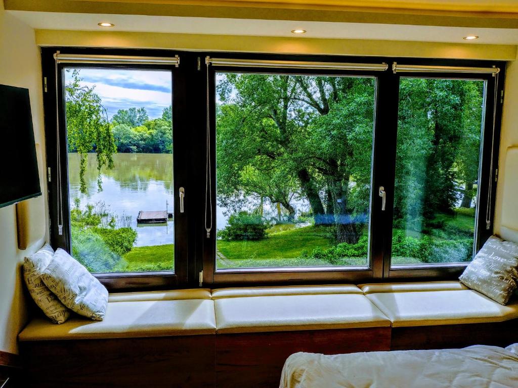 asiento junto a la ventana en una habitación con vistas al lago en Vízparti Apartmanház, en Leányfalu