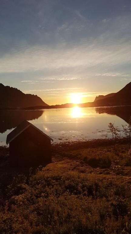 una puesta de sol sobre un cuerpo de agua con un edificio en Rabben Feriested, en Lyngværet
