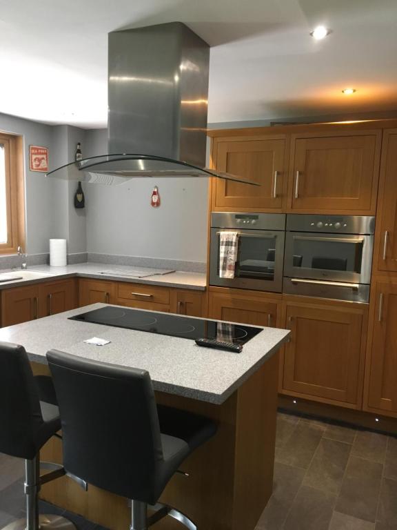 a kitchen with wooden cabinets and a kitchen island with chairs at No 14 in Portsmouth
