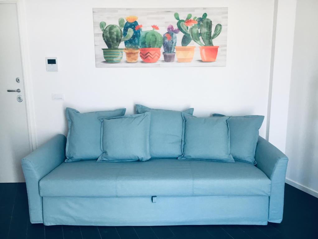 un divano blu in una stanza con una foto di cactus di Appartamento 13 a Polignano a Mare