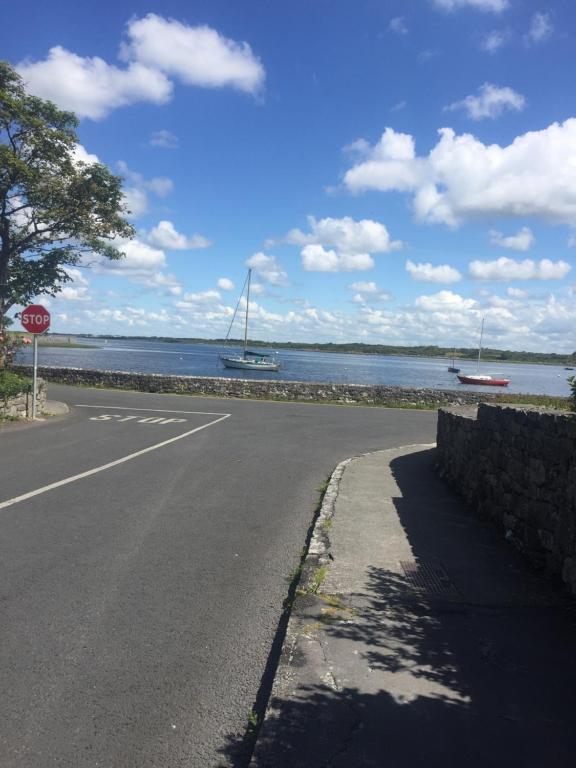 a road with a stop sign and boats in the water at Glebe cottage in Kinvara