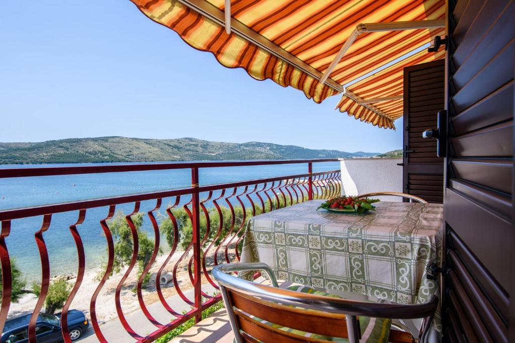 a balcony with a table and chairs and the ocean at Apartments VV in Seget Vranjica