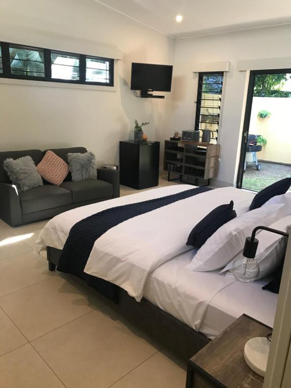 a bedroom with a large bed and a couch at Bali inspired hideaway with Tropical villa & Plunge Pool in Nightcliff