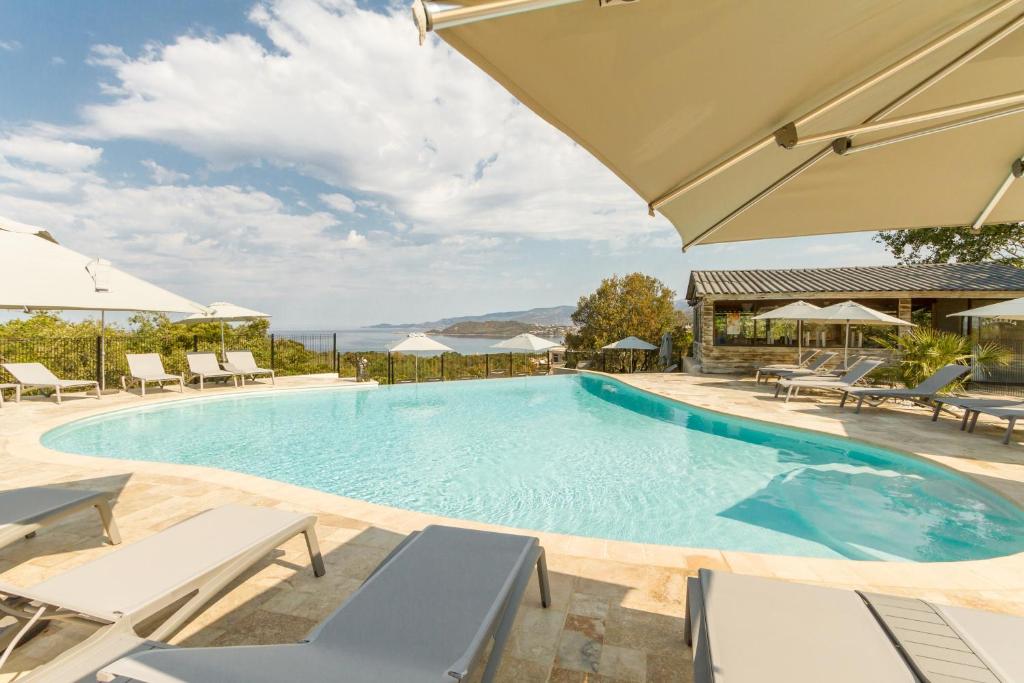 a large swimming pool with chairs and umbrellas at Corsica Paradise in Calcatoggio