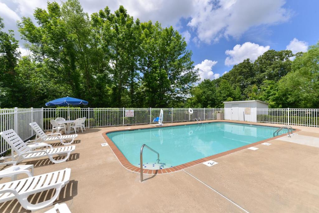 uma piscina com cadeiras e um guarda-sol em The Heritage Inn, Inc em Huntingdon