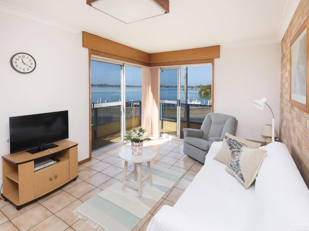 a living room with a couch and a tv and a table at Fairholme 12 in Tuncurry