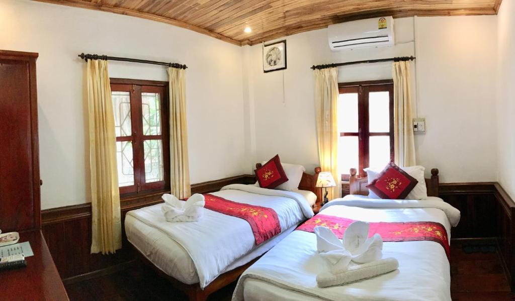 two beds in a room with two windows at Villay Vanh Place House in Luang Prabang