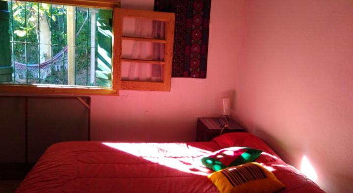 1 dormitorio con cama roja y ventana en Habitación en Casa Las Dos Nenas en Río Ceballos