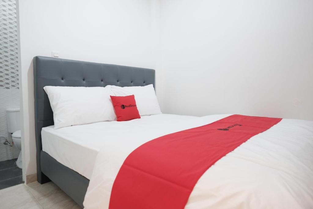 a bed with a red and white blanket on it at RedDoorz near Taman Palem in Jakarta