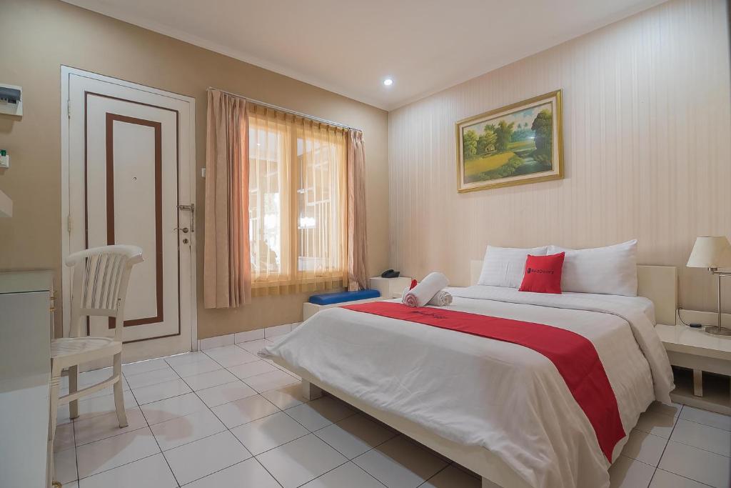 um quarto com uma cama grande e um cobertor vermelho em RedDoorz near Setrasari Mall 2 em Bandung