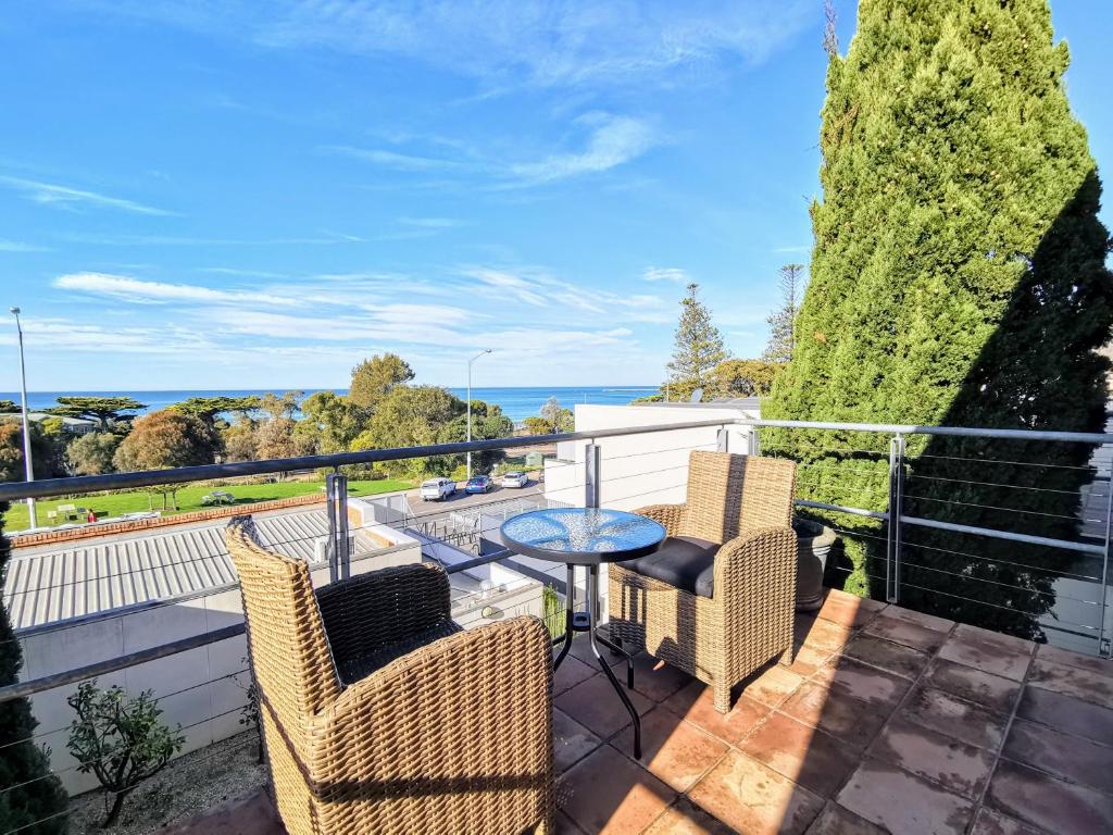 a balcony with wicker chairs and a table with a view at Phoenix Apartments in Lorne