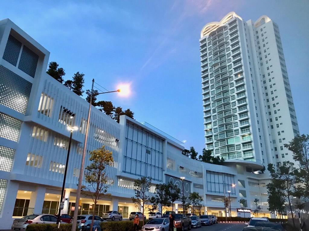 峇六拜的住宿－Southbay Plaza Condominium，停车场内停放汽车的大型建筑