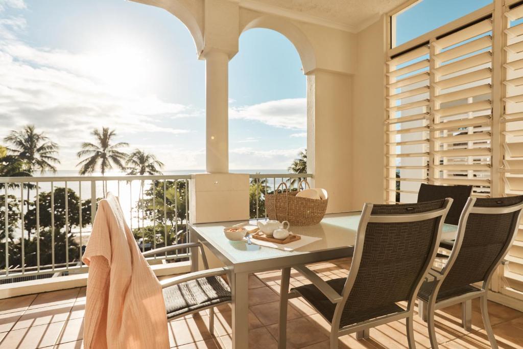 a patio with a table and chairs on a balcony at Sea Change Beachfront Apartments in Trinity Beach