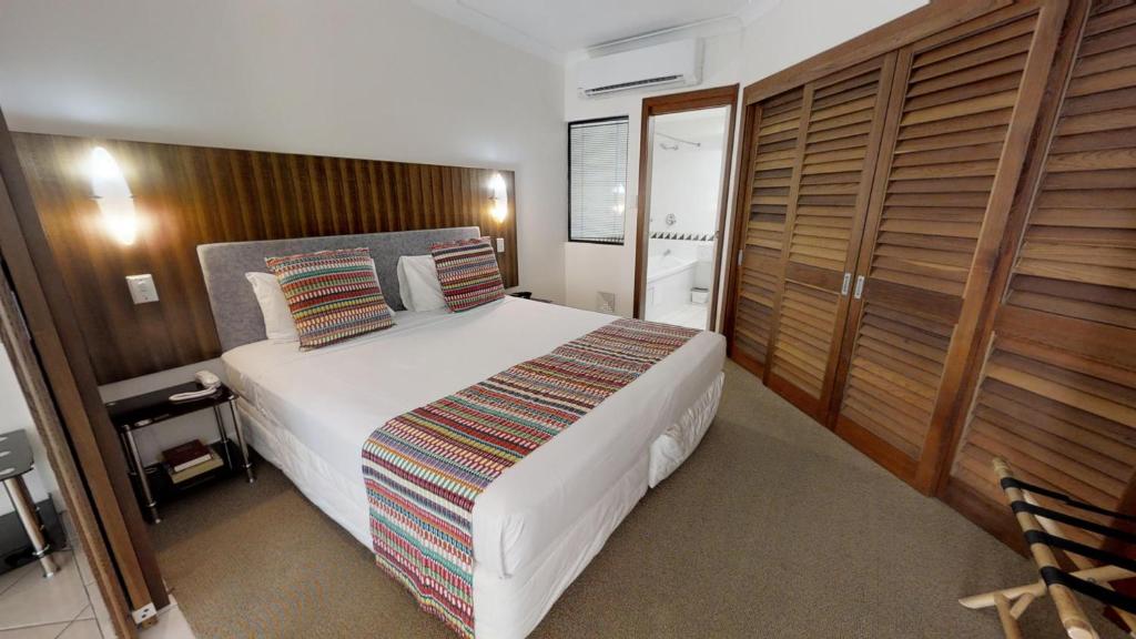 
a bedroom with a bed and a dresser at The Pavilions in Port Douglas
