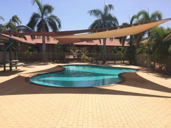 a small swimming pool in a yard with an umbrella at Latitude20 Karratha Apartments in Karratha