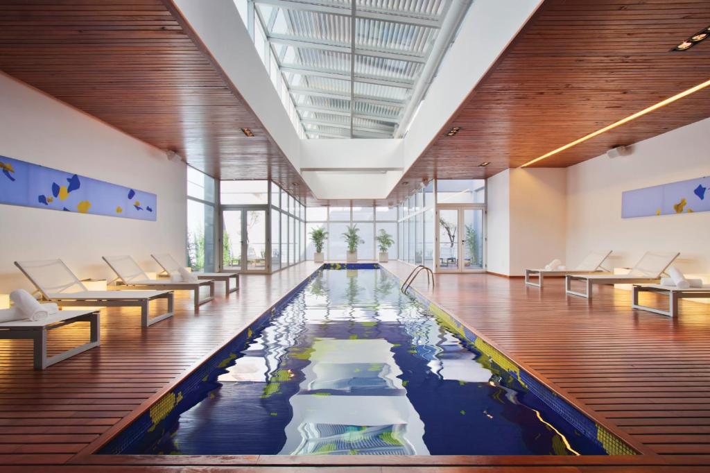 an indoor pool with chairs and tables in a building at Design Suites Buenos Aires in Buenos Aires