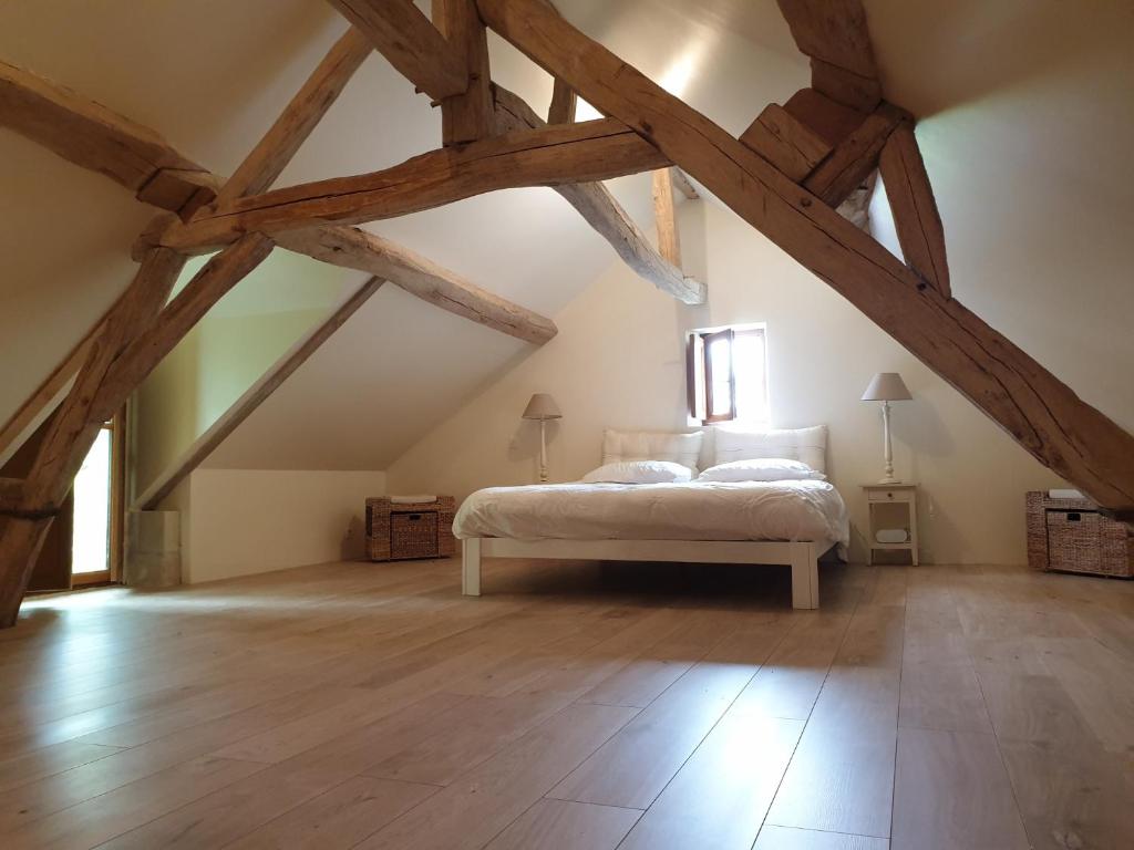 a bedroom with a bed in an attic with wooden beams at Bois logis in Bléré