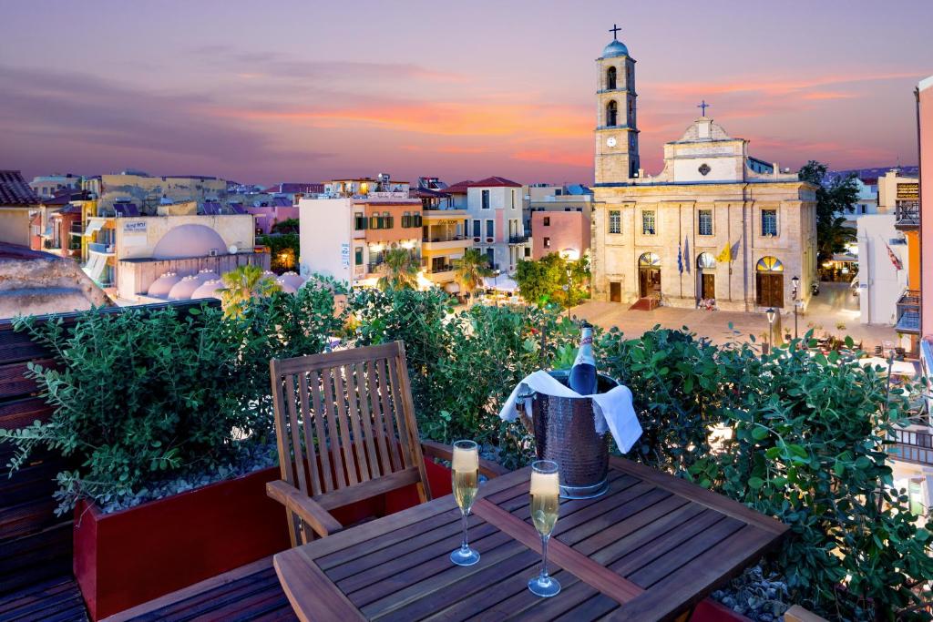 a table with wine glasses on a balcony with a church at Vener Luxury Suites in Chania Town