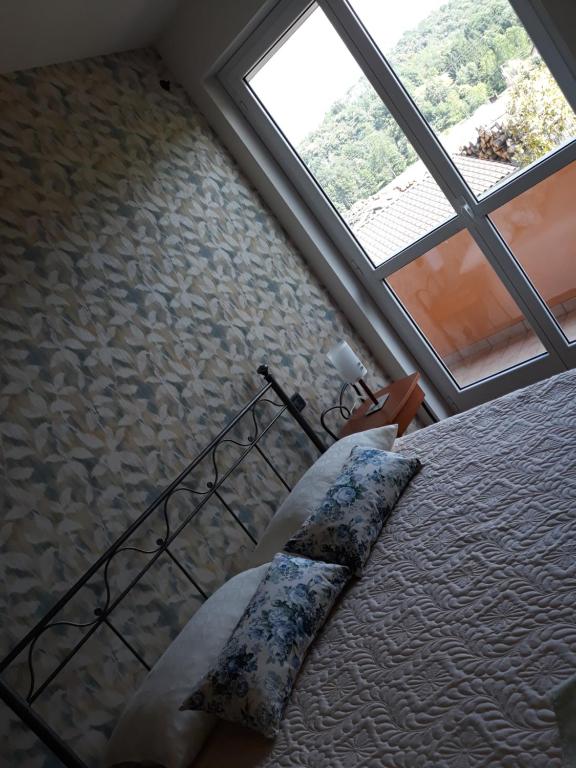een slaapkamer met een bed en een groot raam bij ACERO ROSSO in Pianfei