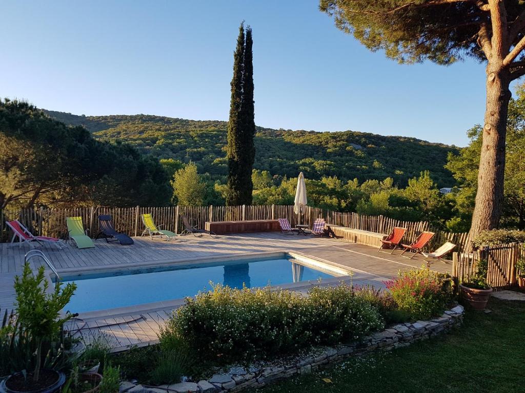 a swimming pool in a yard with chairs and a tree at Mas des Ballats in Saint-Bauzille-de-Putois