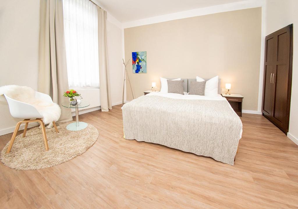 a white bedroom with a bed and a chair at Gästehaus fliegendes Perlhuhn Borgfeld in Lilienthal