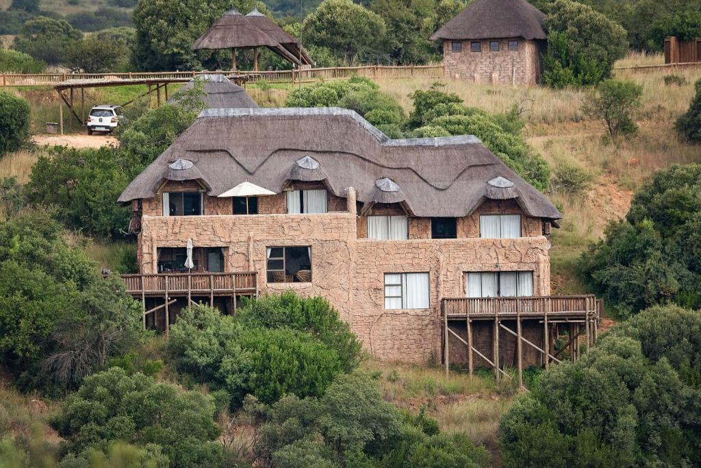 een oud stenen huis met een dak op een heuvel bij Mahikeng Lodge in Magaliesburg