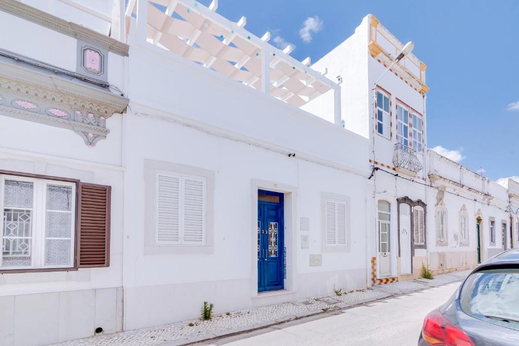 een wit gebouw met een blauwe deur op een straat bij Terrasse Blanche in Olhão