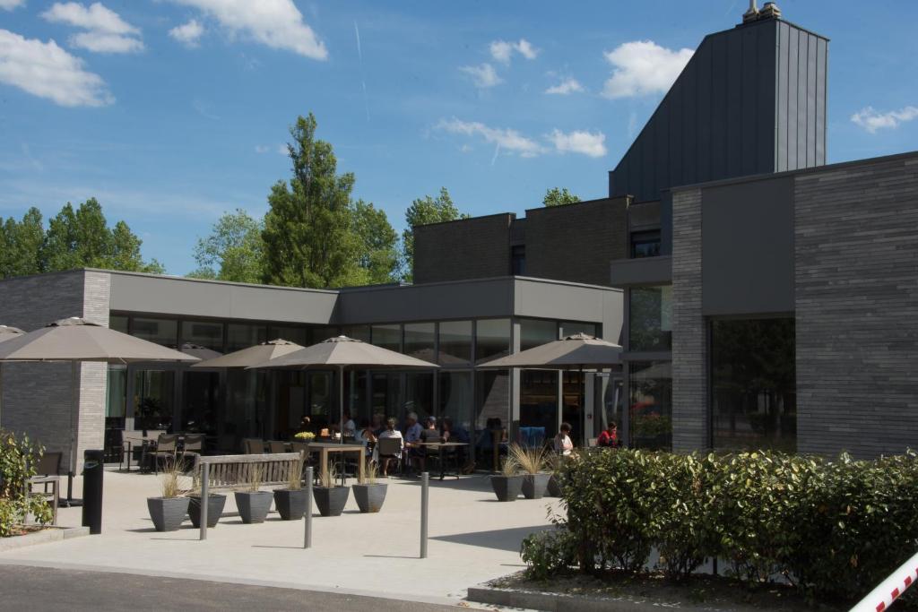 un bâtiment avec des tables et des parasols devant lui dans l'établissement Vakantie Domein Ter Helme, à Oostduinkerke