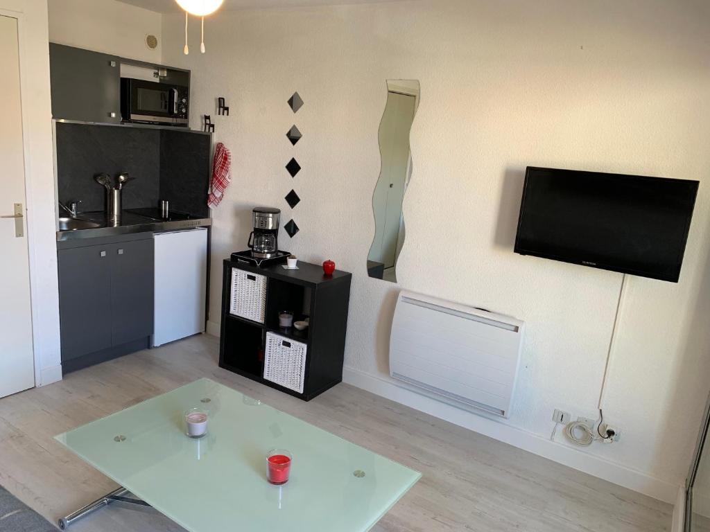 a living room with a table and a tv on a wall at Studio cabine au Grau du roi à 3min à pied de la plage in Le Grau-du-Roi