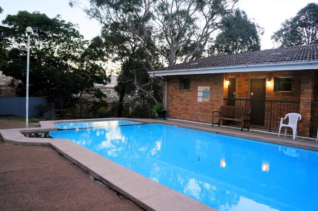 a swimming pool in front of a house at Panorama Motor Inn in Newcastle