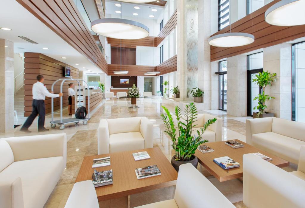 an office lobby with white furniture and a man pushing a cart at Arfa Park-Hotel in Adler