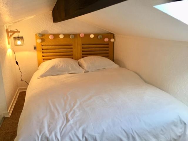 1 dormitorio con cama blanca y cabecero de madera en Maison à l'Amélie Plage, 300 mètres de la plage/mer, en Soulac-sur-Mer