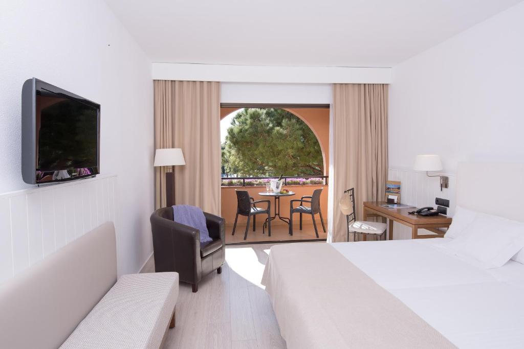 a hotel room with a bed and a table and chairs at La Costa Hotel Golf & Beach Resort in Pals