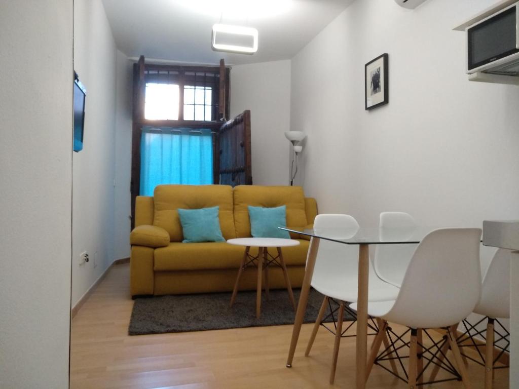 Una sala de estar con un sofá amarillo y una mesa. en El Patio del Convento, en Toledo