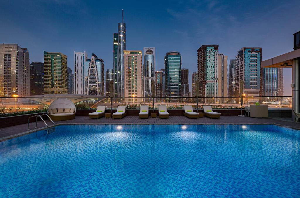 einen Hotelpool mit einer Skyline der Stadt im Hintergrund in der Unterkunft Millennium Place Dubai Marina in Dubai